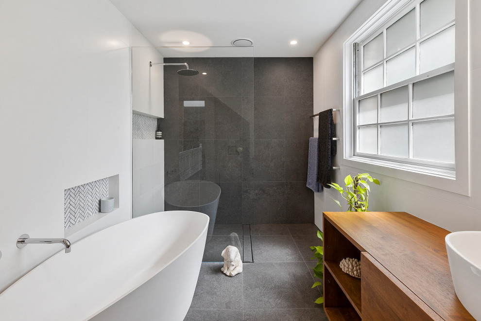 Design ideas for a mid-sized contemporary master bathroom in Sydney with dark wood cabinets, a freestanding tub, an open shower, white tile, porcelain tile, white walls, porcelain floors, a vessel sink, wood benchtops, grey floor and an open shower.