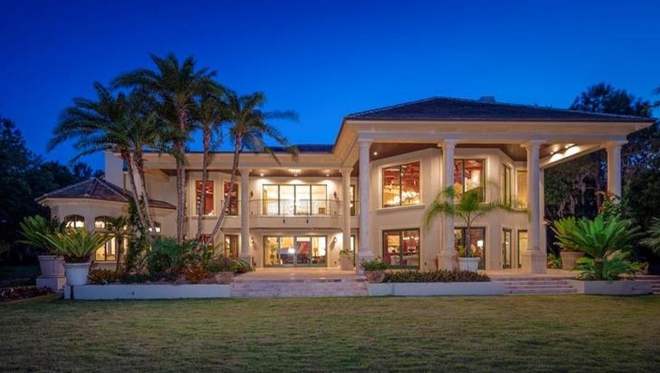 Expansive traditional two-storey green exterior in Orlando with stone veneer and a hip roof.