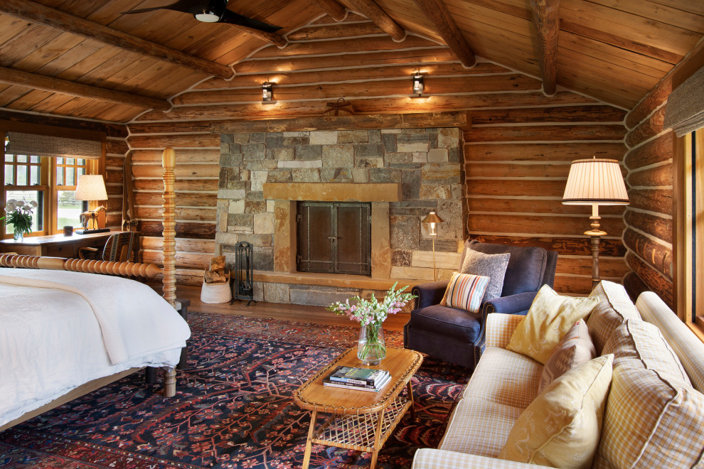 Inspiration for a country master bedroom in Other with a standard fireplace, exposed beam, vaulted, wood, brown walls, medium hardwood floors, a stone fireplace surround, brown floor and wood walls.