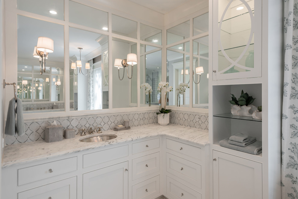 This is an example of a large traditional master bathroom in Charleston with white cabinets, a freestanding tub, a one-piece toilet, gray tile, grey walls, white floor and white benchtops.