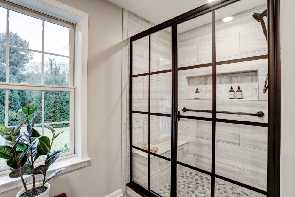 Пример оригинального дизайна: главная ванная комната среднего размера в стиле неоклассика (современная классика) с фасадами с утопленной филенкой, серыми фасадами, душем в нише, унитазом-моноблоком, серыми стенами, полом из винила, монолитной раковиной, столешницей из гранита, серым полом, душем с раздвижными дверями, серой столешницей, сиденьем для душа, тумбой под две раковины и встроенной тумбой