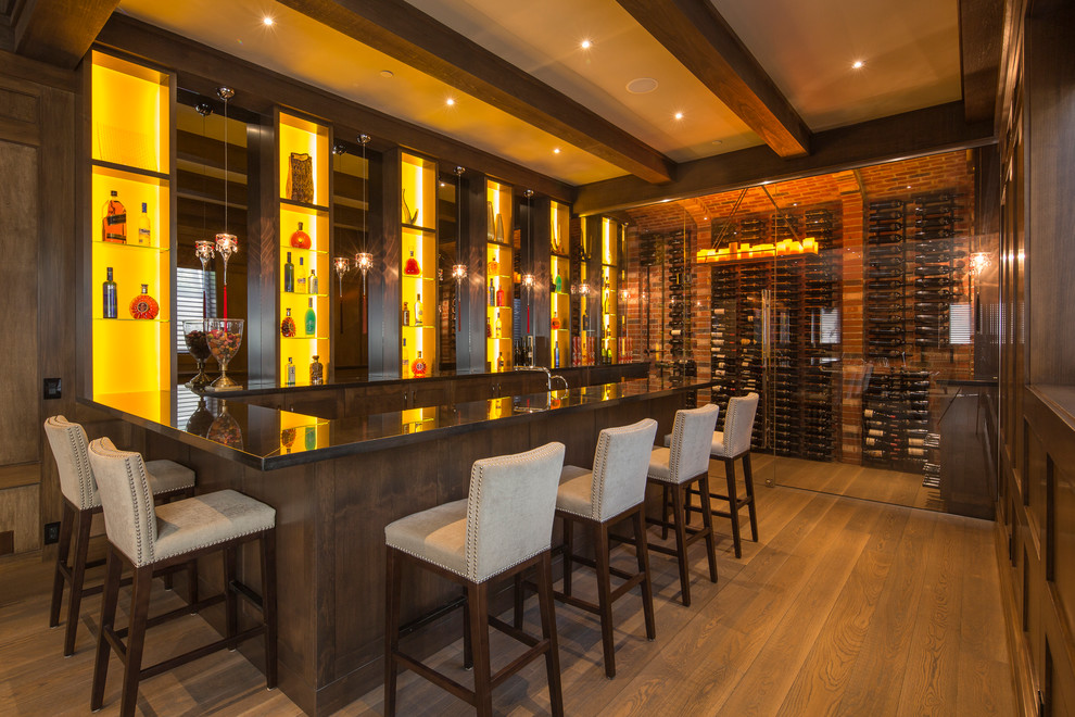 This is an example of an expansive traditional galley seated home bar in Vancouver with open cabinets, brown splashback, medium hardwood floors, dark wood cabinets and marble benchtops.