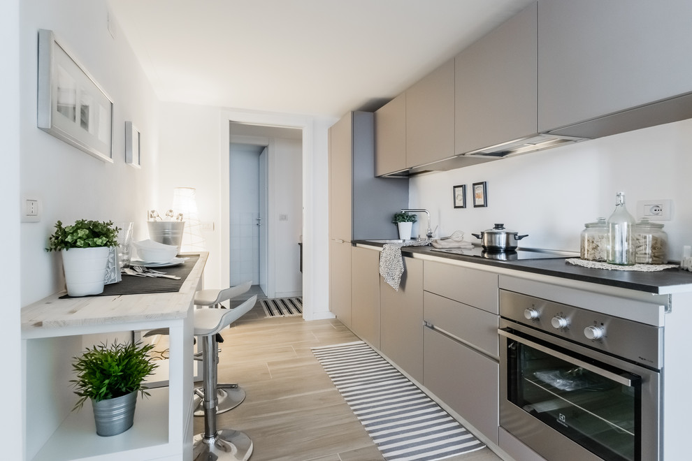 Inspiration for a mid-sized contemporary single-wall eat-in kitchen in Milan with flat-panel cabinets, grey cabinets, white splashback, stainless steel appliances, porcelain floors, no island and brown floor.