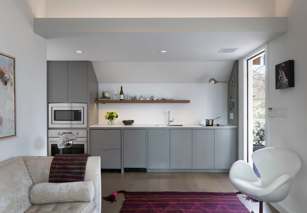 Inspiration for a small contemporary single-wall open plan kitchen in Austin with flat-panel cabinets, grey cabinets, white splashback, stainless steel appliances, dark hardwood floors and no island.