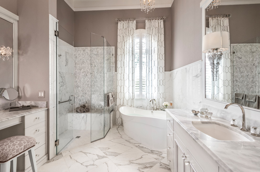 Photo of a large transitional master bathroom in Miami with white cabinets, a freestanding tub, a corner shower, ceramic tile, brown walls, marble floors, an undermount sink, marble benchtops, multi-coloured floor, a hinged shower door, multi-coloured benchtops, flat-panel cabinets and gray tile.