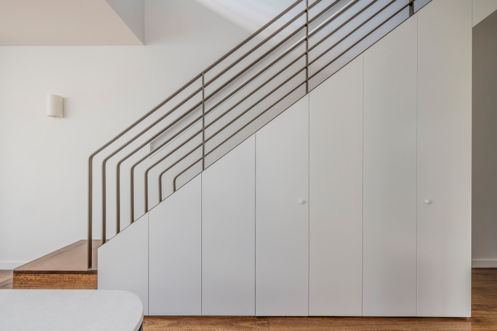 Immagine di una scala curva minimalista di medie dimensioni con pedata in metallo, alzata in legno e parapetto in metallo