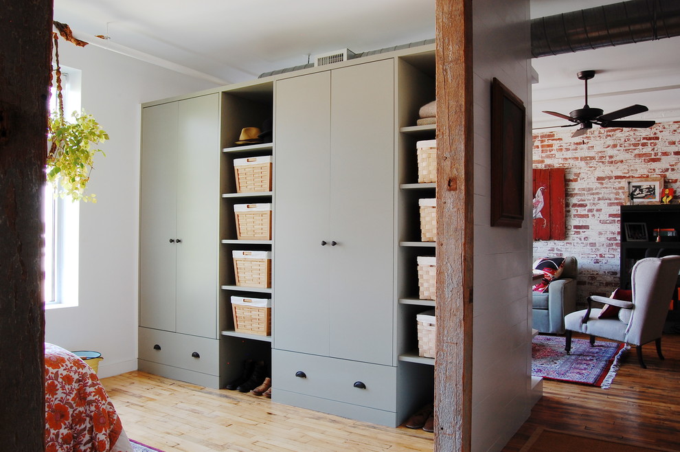 Design ideas for an industrial storage and wardrobe in New York with light hardwood floors.