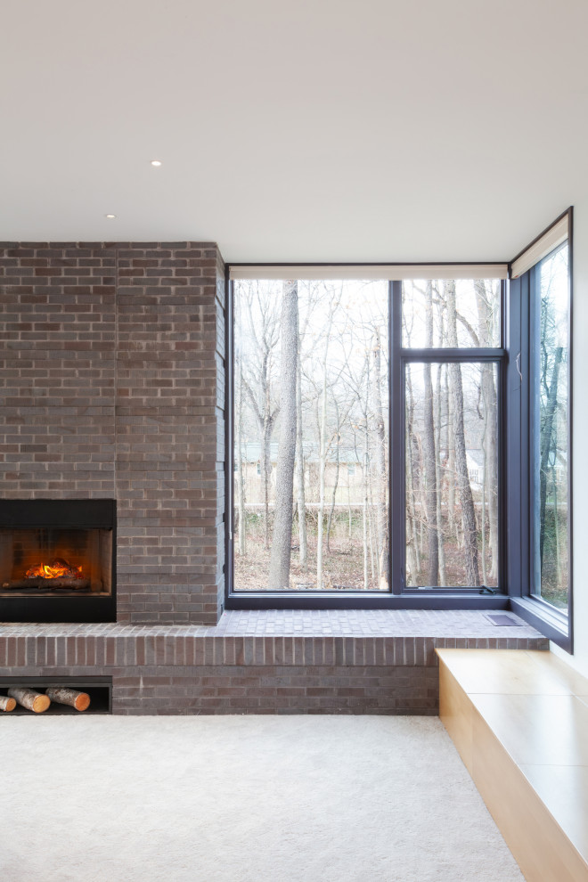 Photo of a modern open concept living room in Indianapolis with white walls, carpet, a wood stove, a brick fireplace surround, a wall-mounted tv and beige floor.