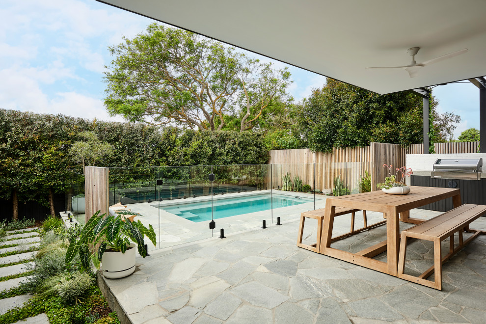 This is an example of a mid-sized contemporary backyard rectangular pool in Geelong with natural stone pavers.