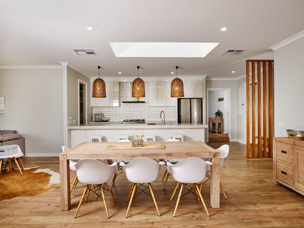 Large modern kitchen/dining combo in Other with grey walls, laminate floors and brown floor.