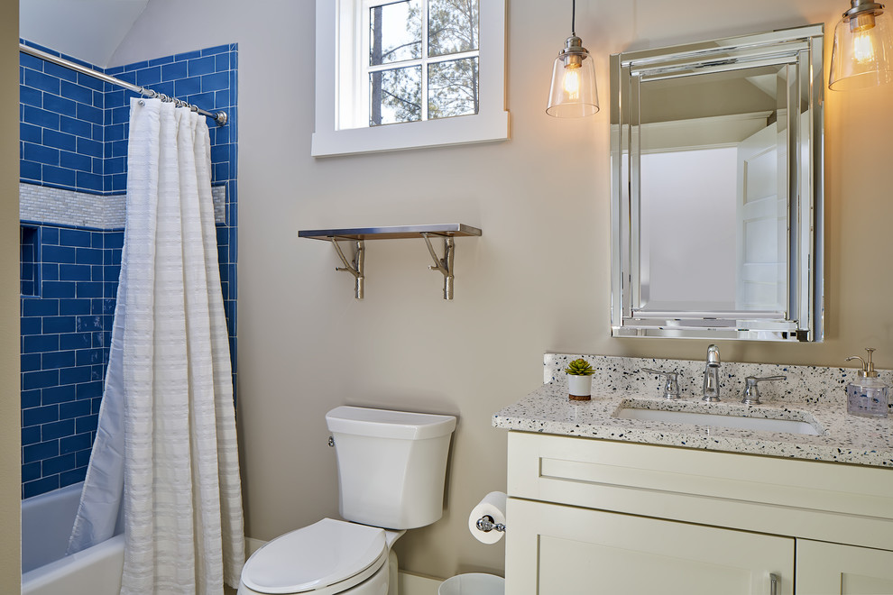 Photo of a mid-sized transitional 3/4 bathroom in Atlanta with shaker cabinets, white cabinets, an alcove tub, a shower/bathtub combo, a one-piece toilet, blue tile, subway tile, beige walls, an undermount sink and recycled glass benchtops.