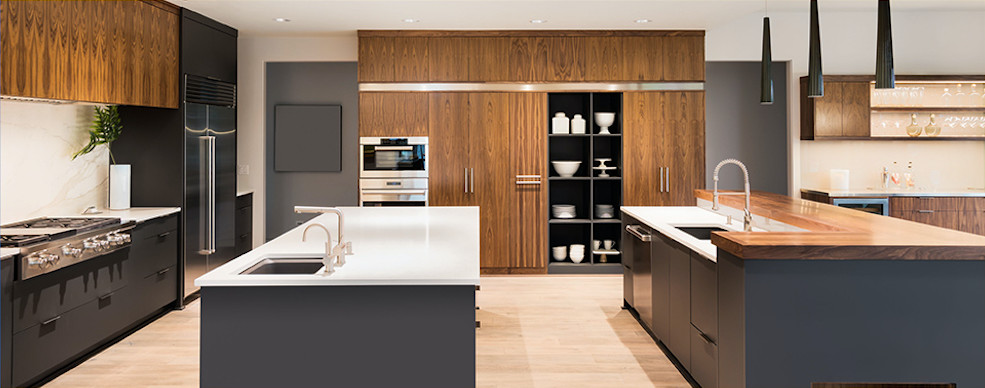 Inspiration for an expansive contemporary l-shaped kitchen in Other with an undermount sink, flat-panel cabinets, dark wood cabinets, solid surface benchtops, panelled appliances, light hardwood floors, multiple islands, beige floor and white benchtop.