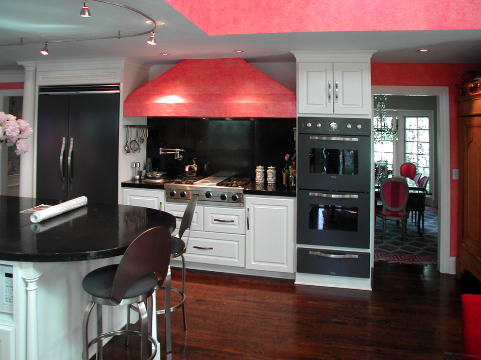 Traditional kitchen in Kansas City with raised-panel cabinets, white cabinets, granite benchtops, black splashback, stone slab splashback and black appliances.