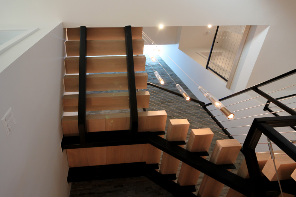 Modelo de escalera suspendida ecléctica grande con escalones de madera, barandilla de metal y ladrillo