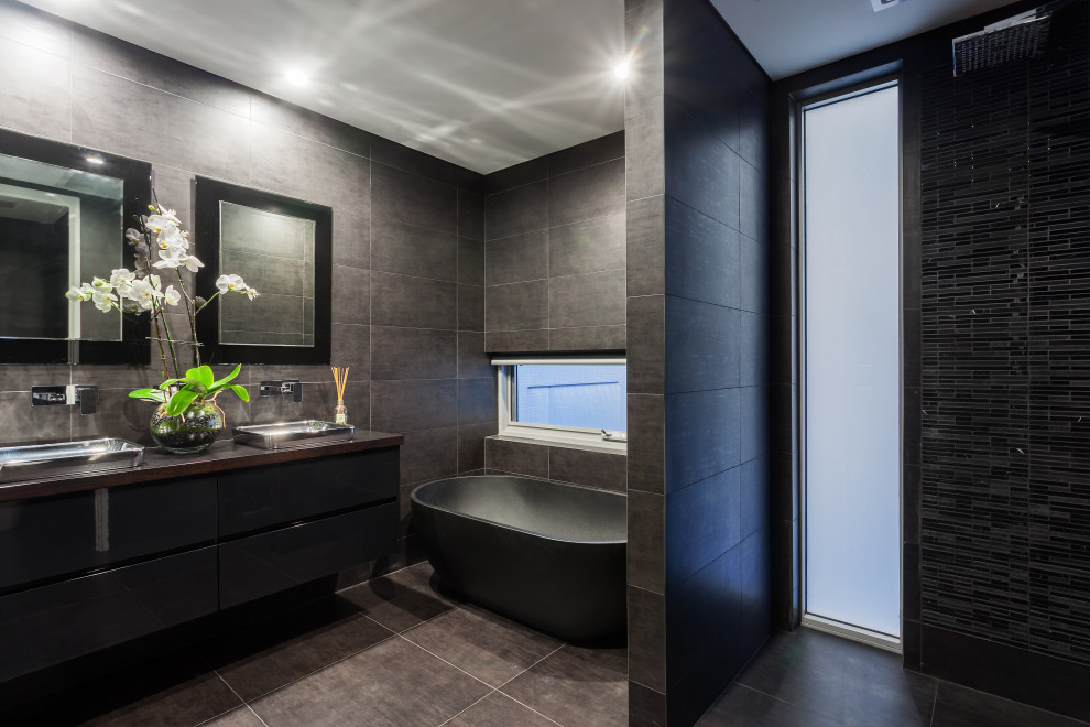 Inspiration for a modern bathroom in Perth with flat-panel cabinets, black cabinets, a freestanding tub, an open shower, brown tile, ceramic tile, ceramic floors, a vessel sink, wood benchtops, brown floor, an open shower, brown benchtops, a double vanity and a built-in vanity.