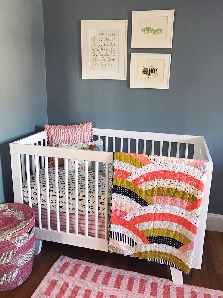 Design ideas for a mid-sized scandinavian nursery for girls in New York with grey walls and medium hardwood floors.