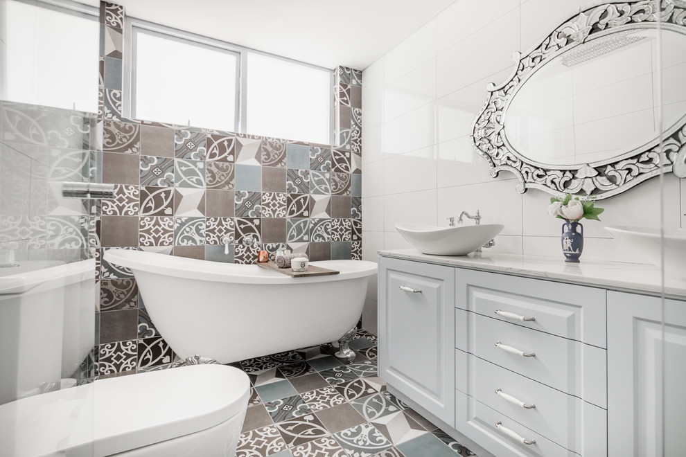 This is an example of a mid-sized country master bathroom in Sydney with blue cabinets, a claw-foot tub, a double shower, white tile, porcelain tile, mosaic tile floors, marble benchtops, multi-coloured floor and a hinged shower door.