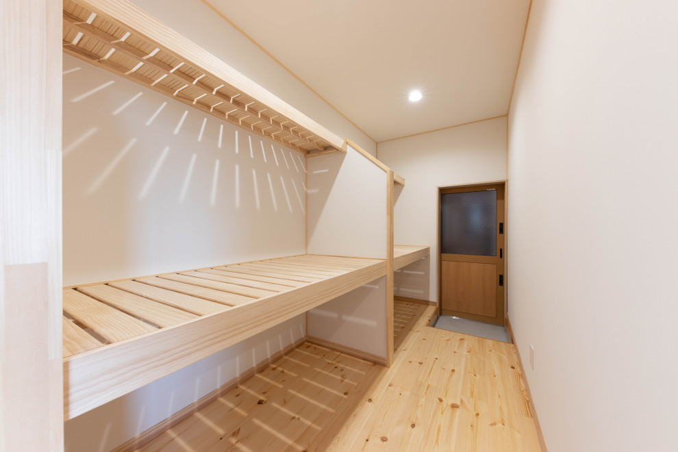 Diseño de armario y vestidor de estilo zen pequeño con suelo de madera clara, suelo beige y papel pintado