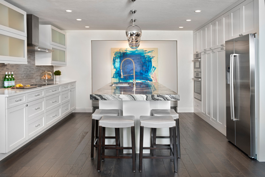 Design ideas for a mid-sized contemporary single-wall open plan kitchen in Tampa with an undermount sink, shaker cabinets, white cabinets, glass tile splashback, stainless steel appliances, dark hardwood floors, with island, marble benchtops, grey splashback and brown floor.