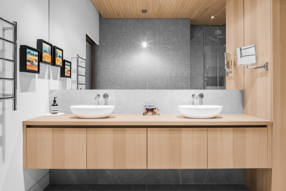 Aménagement d'une salle de bain principale montagne en bois clair de taille moyenne avec un placard à porte plane, un carrelage gris, mosaïque, une vasque, un plan de toilette en bois, un sol gris, meuble double vasque, meuble-lavabo suspendu et un plafond en lambris de bois.