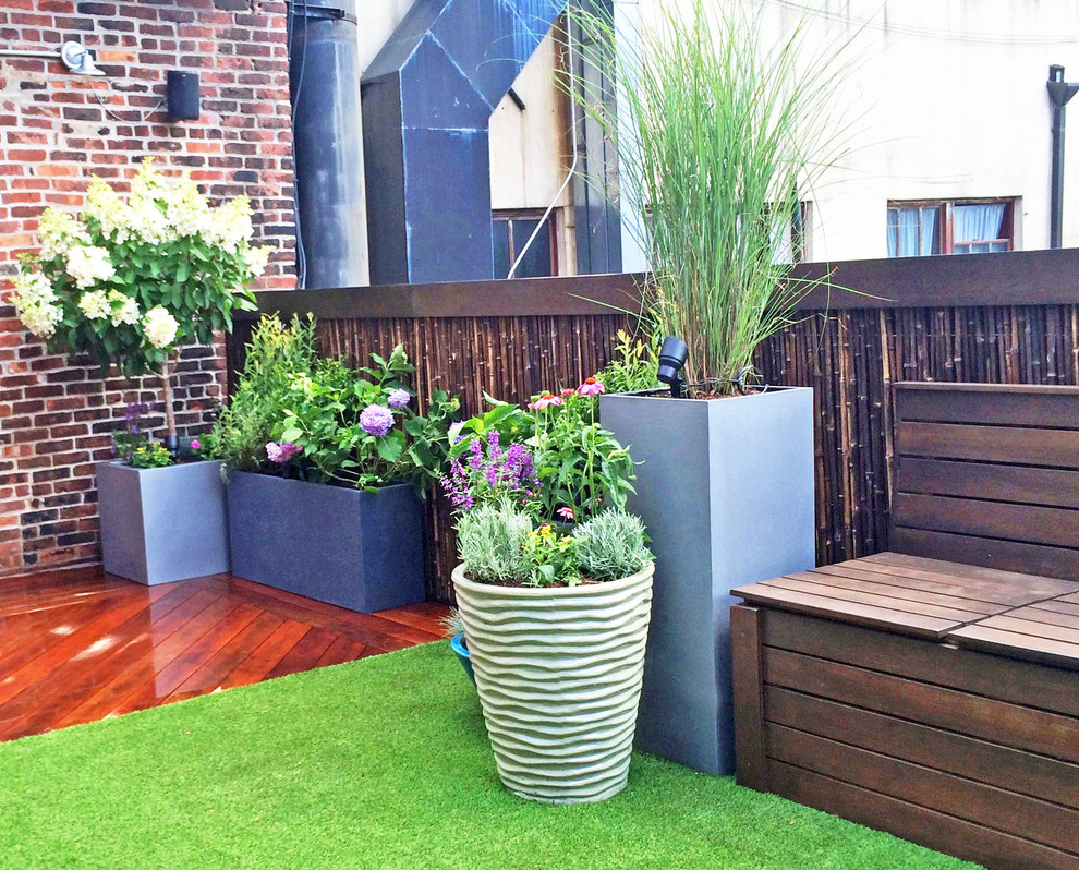 This is an example of a contemporary rooftop full sun garden for summer in New York with a container garden and decking.