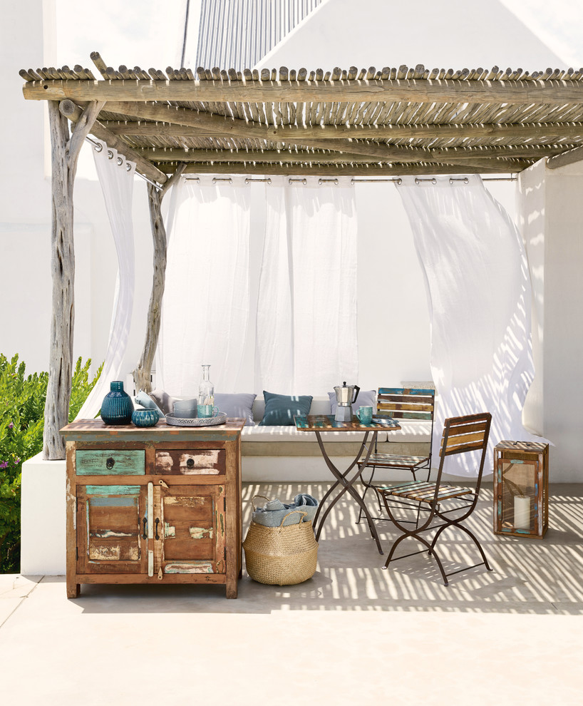 Mid-sized beach style patio in London with a pergola.