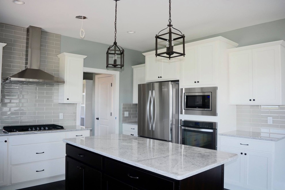 Open concept kitchen - large transitional l-shaped dark wood floor open concept kitchen idea with an undermount sink, shaker cabinets, white cabinets, granite countertops, gray backsplash, porcelain backsplash, stainless steel appliances and an island