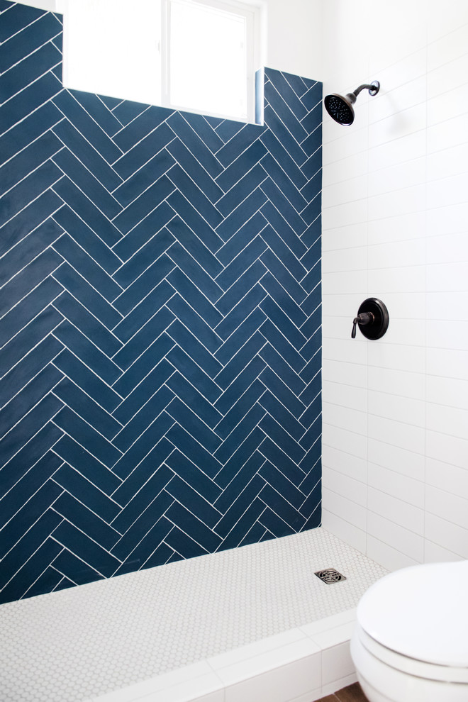 Inspiration for a mid-sized transitional 3/4 bathroom in San Diego with shaker cabinets, blue cabinets, an alcove shower, a two-piece toilet, white tile, subway tile, white walls, dark hardwood floors, an undermount sink, solid surface benchtops, brown floor and white benchtops.