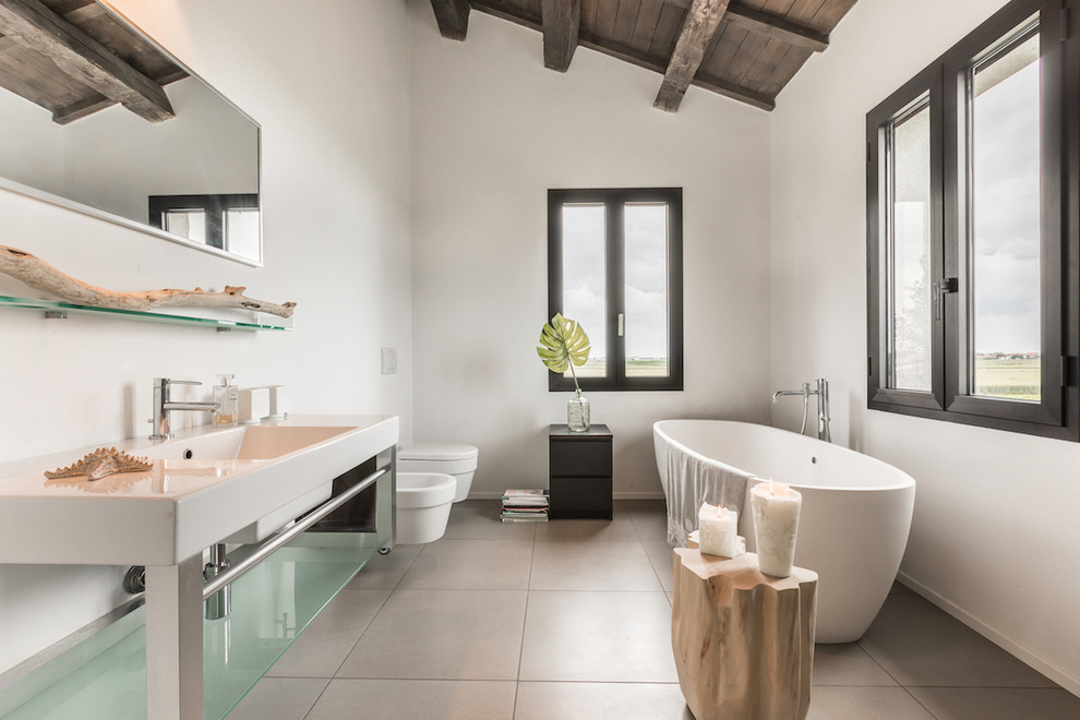 This is an example of a contemporary bathroom in Other with a freestanding tub, white walls, an integrated sink, grey floor and white benchtops.