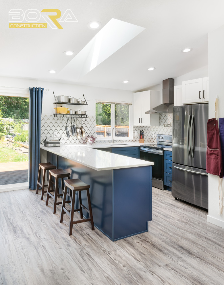 Inspiration for a small u-shaped eat-in kitchen in Seattle with an undermount sink, shaker cabinets, blue cabinets, quartz benchtops, grey splashback, ceramic splashback, stainless steel appliances, medium hardwood floors, a peninsula, grey floor and white benchtop.