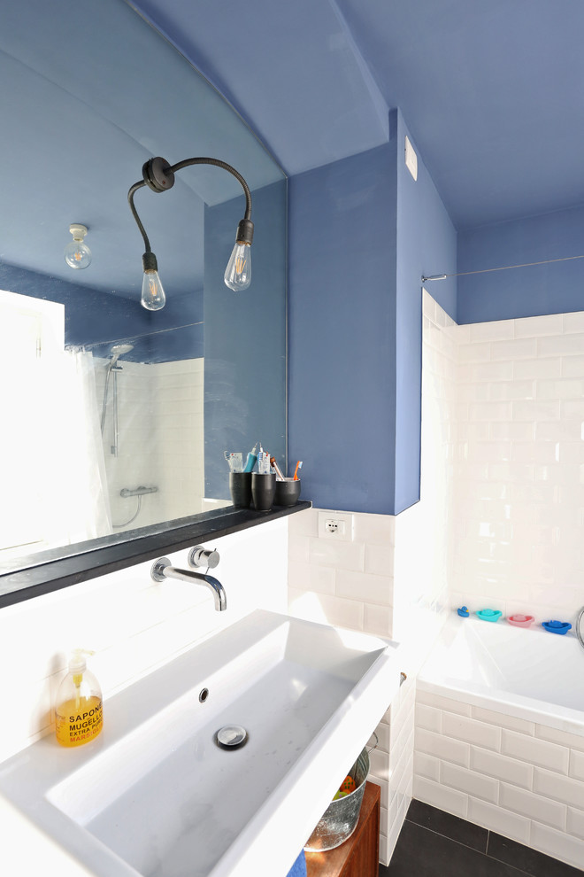 Photo of a small mediterranean powder room in Other with a wall-mount toilet, white tile, subway tile, blue walls, porcelain floors, a wall-mount sink and black floor.