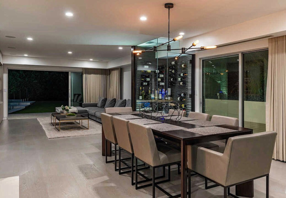 Photo of a large contemporary open plan dining in Los Angeles with white walls, medium hardwood floors, a two-sided fireplace, a stone fireplace surround and grey floor.