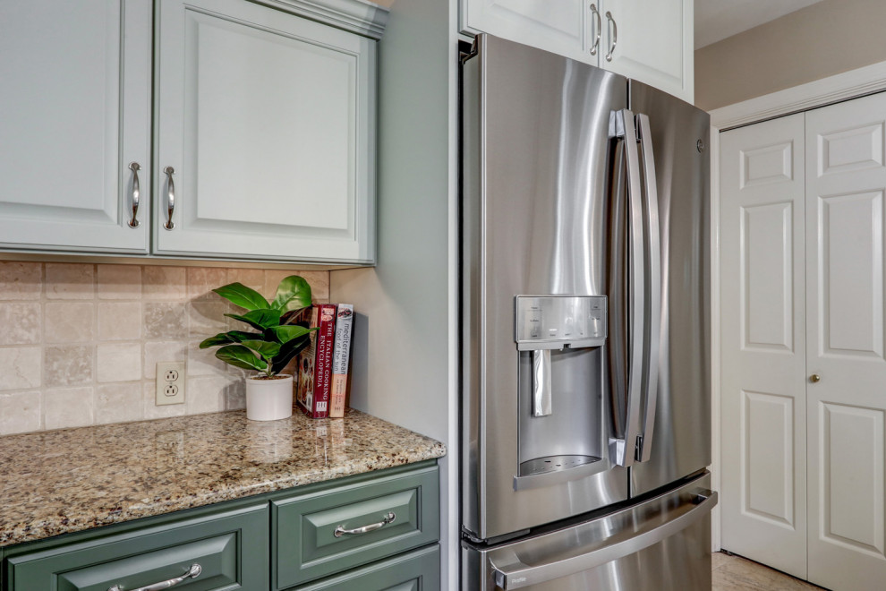 Example of a mid-sized transitional l-shaped ceramic tile and beige floor eat-in kitchen design with a double-bowl sink, raised-panel cabinets, green cabinets, granite countertops, beige backsplash, ceramic backsplash, stainless steel appliances, an island and beige countertops
