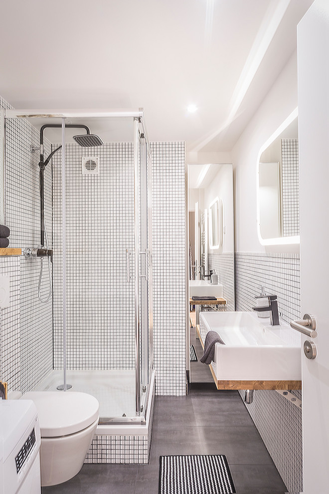 Modern bathroom in Dusseldorf with a wall-mount toilet, white walls, a vessel sink, grey floor and a hinged shower door.