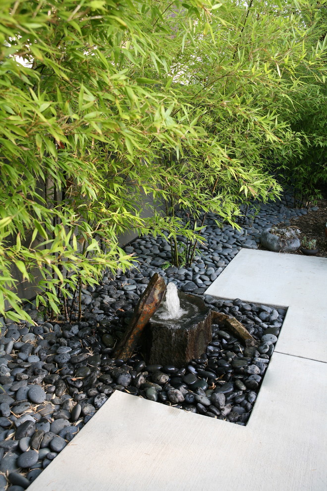 Photo of a mid-sized asian backyard full sun formal garden in Orange County with a water feature and natural stone pavers.