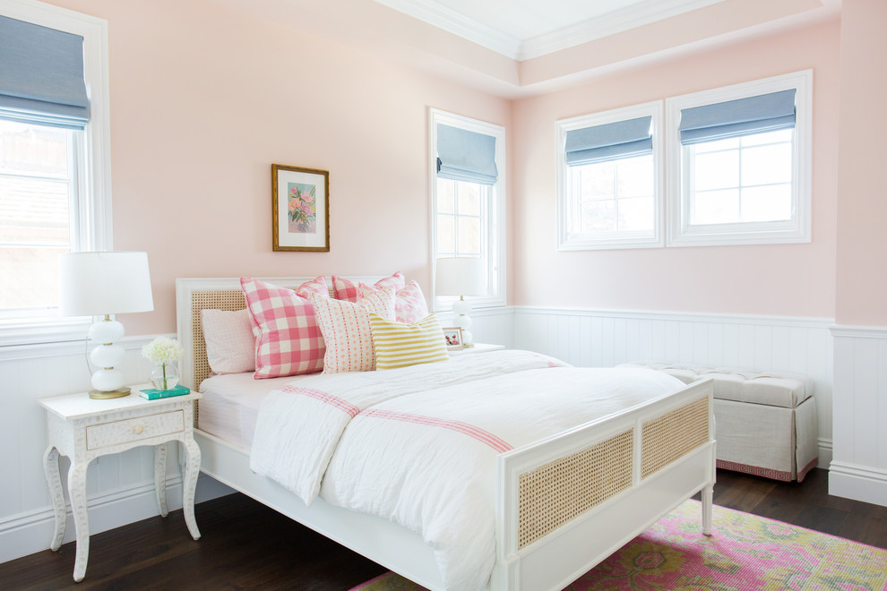 Photo of a transitional kids' bedroom for girls in Los Angeles with pink walls and dark hardwood floors.