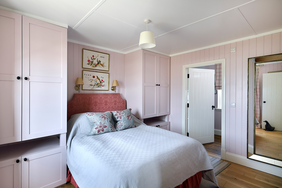 Photo of a mid-sized country bedroom in Glasgow with pink walls, light hardwood floors and brown floor.