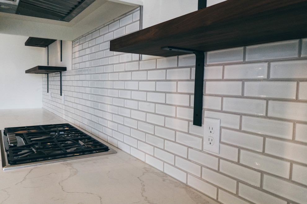 Enclosed kitchen - transitional dark wood floor enclosed kitchen idea in Omaha with a farmhouse sink, shaker cabinets, white cabinets, quartz countertops, white backsplash, paneled appliances and an island