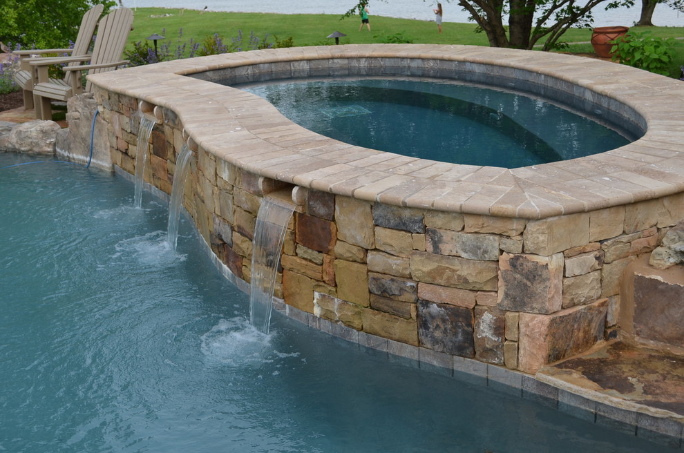 Inspiration for an expansive traditional backyard custom-shaped infinity pool in Other with a water feature and natural stone pavers.