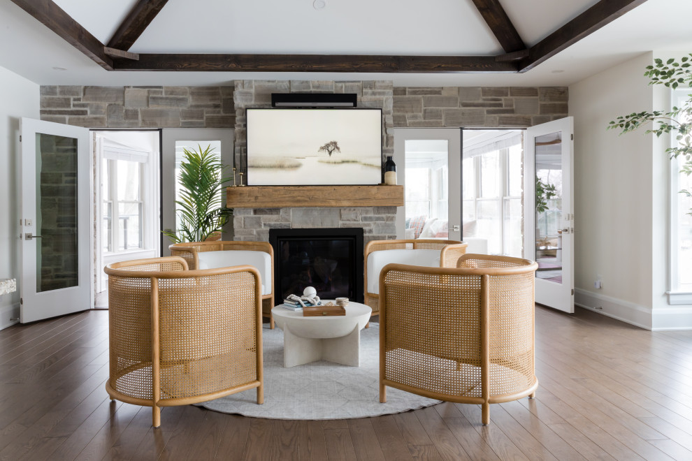 This is an example of a transitional living room in Other with white walls, medium hardwood floors, a standard fireplace, a stone fireplace surround, no tv, brown floor, exposed beam and vaulted.