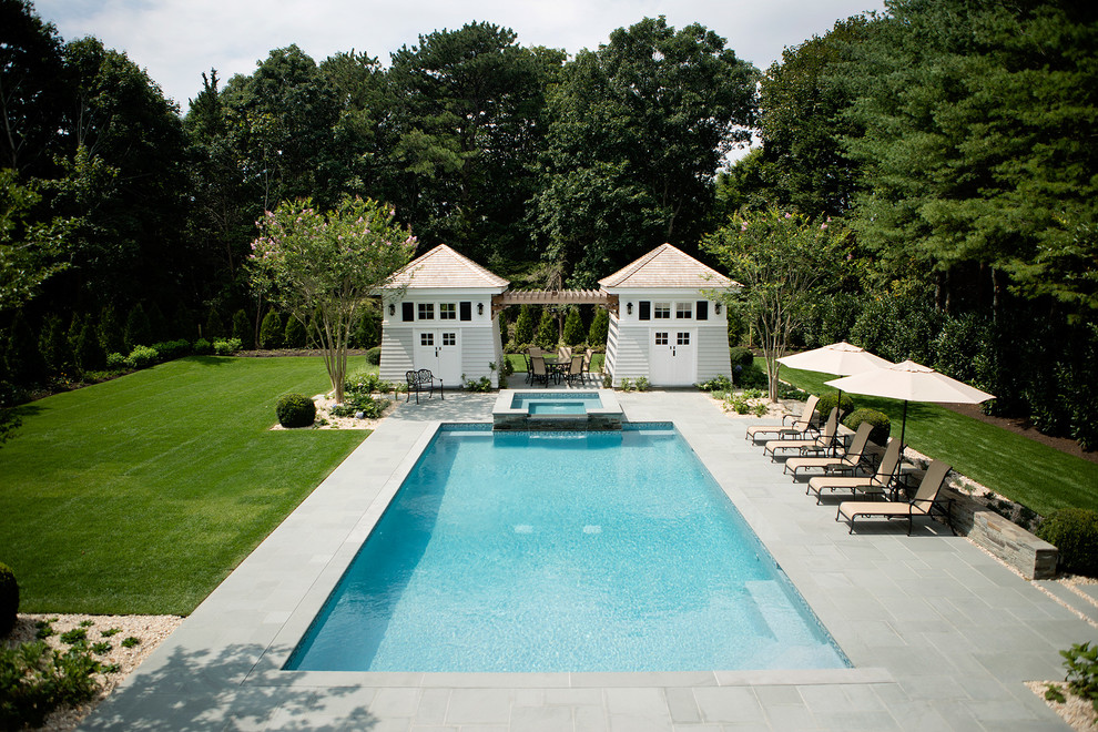 Photo of a large traditional backyard rectangular natural pool in New York with a hot tub and natural stone pavers.