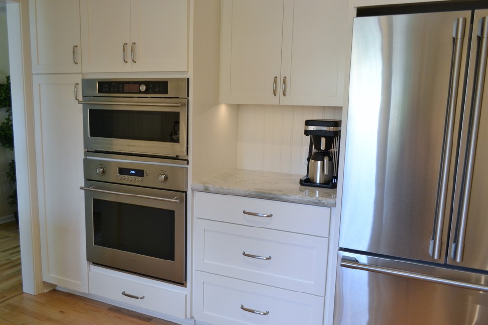 Photo of a mid-sized traditional u-shaped eat-in kitchen in San Francisco with an undermount sink, shaker cabinets, white cabinets, granite benchtops, white splashback, ceramic splashback, stainless steel appliances, medium hardwood floors, brown floor and green benchtop.