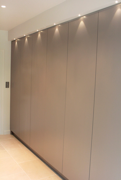 Large contemporary gender-neutral dressing room in London with flat-panel cabinets and grey cabinets.