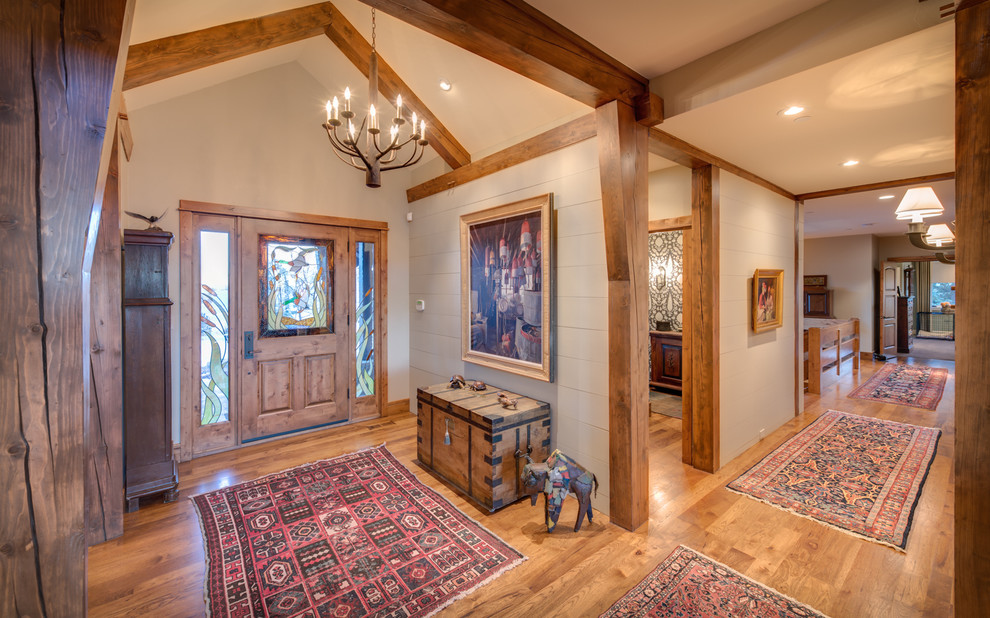 Example of a mountain style medium tone wood floor foyer design in Denver with white walls and a medium wood front door