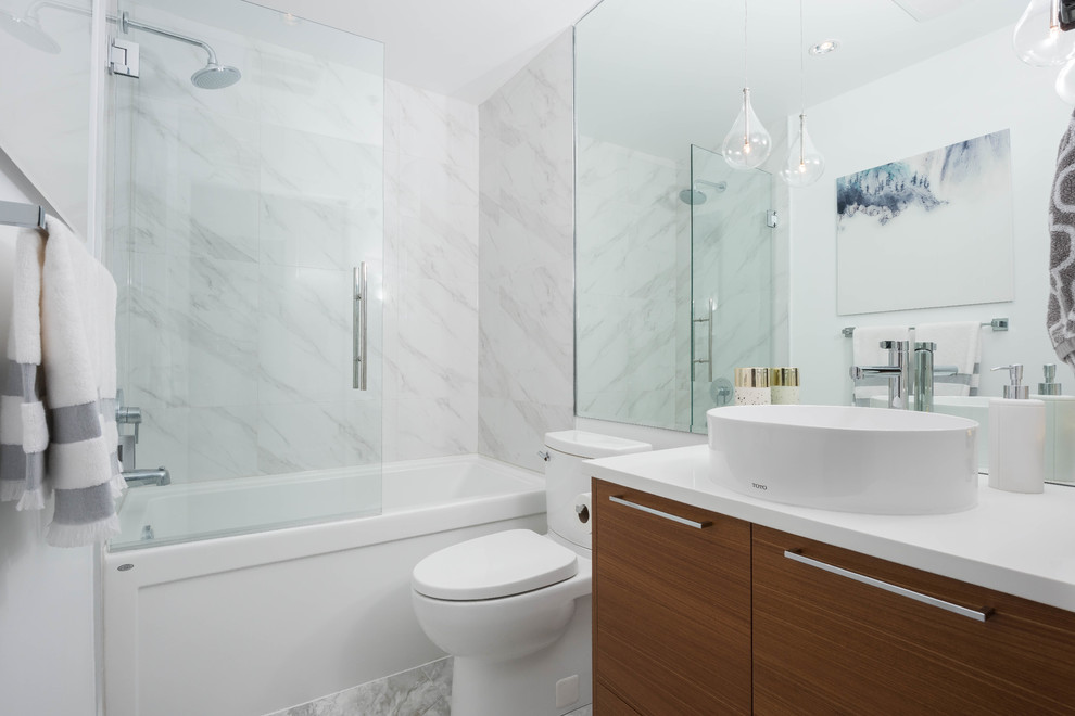Inspiration for a mid-sized contemporary bathroom in Vancouver with medium wood cabinets, an alcove tub, a shower/bathtub combo, a one-piece toilet, white tile, porcelain tile, white walls, a vessel sink, engineered quartz benchtops, grey floor, a hinged shower door and porcelain floors.