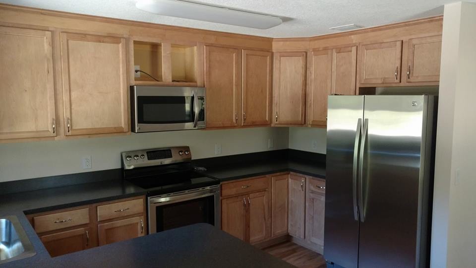 Mid-sized transitional u-shaped medium tone wood floor and brown floor open concept kitchen photo in Orlando with a drop-in sink, recessed-panel cabinets, light wood cabinets, quartz countertops, stainless steel appliances and a peninsula