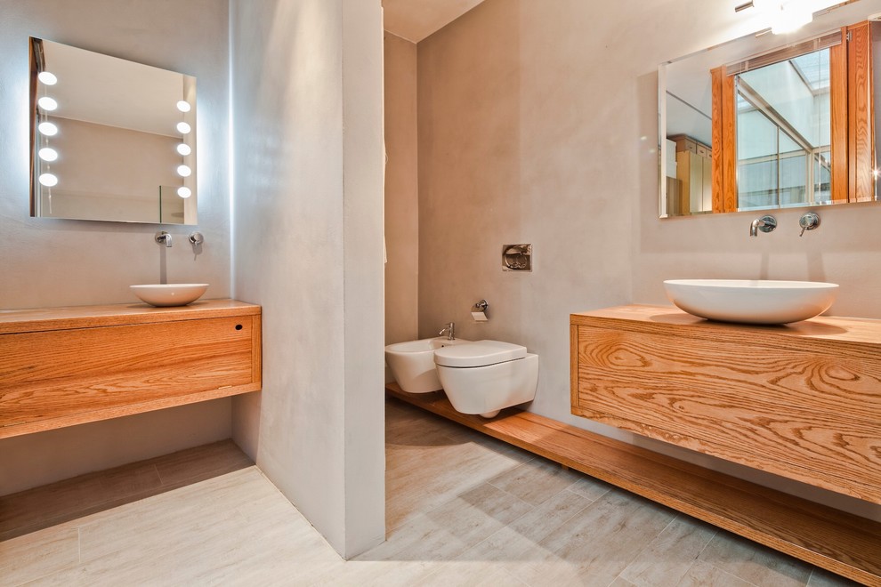 Photo of a scandinavian bathroom in Bologna with flat-panel cabinets, light wood cabinets, beige walls, a vessel sink, wood benchtops and brown benchtops.