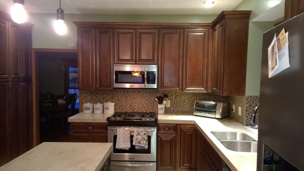 Example of a mid-sized classic l-shaped porcelain tile eat-in kitchen design with a double-bowl sink, raised-panel cabinets, dark wood cabinets, quartz countertops, multicolored backsplash, mosaic tile backsplash, stainless steel appliances and an island