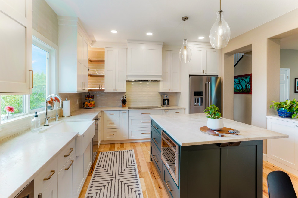 Large transitional l-shaped eat-in kitchen photo in Denver with a farmhouse sink, shaker cabinets, white cabinets, glass tile backsplash, stainless steel appliances and an island