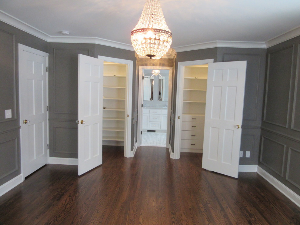 Inspiration for a traditional gender-neutral walk-in wardrobe in Minneapolis with flat-panel cabinets, white cabinets and dark hardwood floors.